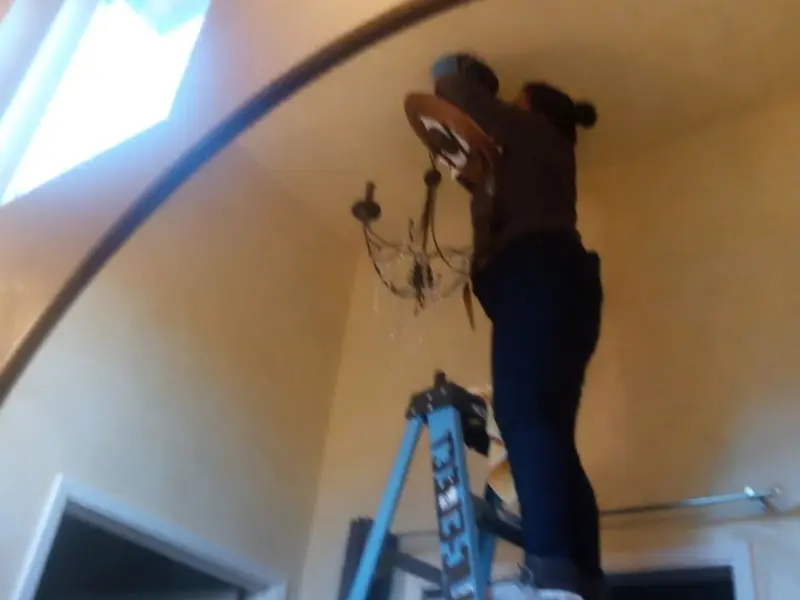 Electrician installing a chandelier in a Concordia residence